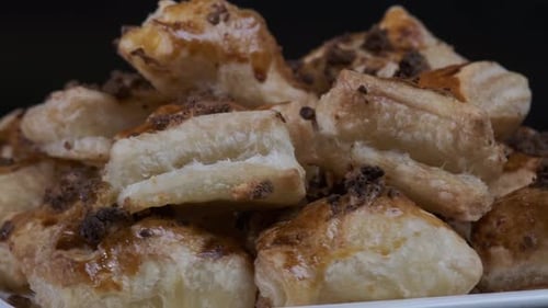 Gebackener Blätterteig mit Toppings. Puffs mit Käse auf weißem Teller, der sich vor der Kamera dreht