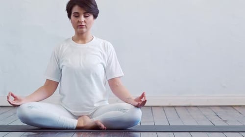 Young and fit woman practicing yoga indoor in the class.