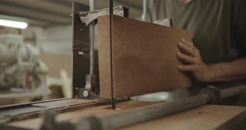 Woodworker Cutting Piece of Wood with Band Saw