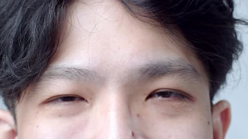 Close up of Asian Man's face. Attractive boy with beautiful eyes. Caucasian young male model with ey