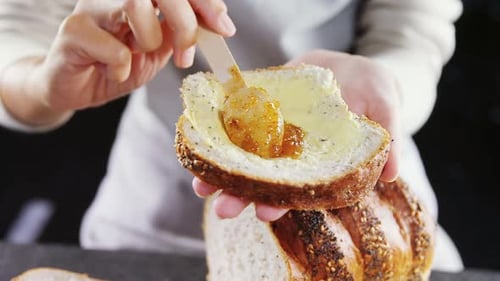 Mujer aplicando mermelada sobre una rebanada de pan multigrano 4k