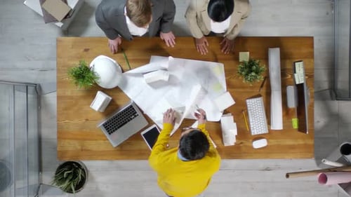 Architects Collaborate on Building Blueprints in Office