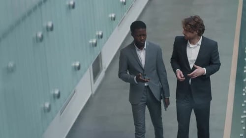 Two Male Colleagues Going along Office Hall and Talking