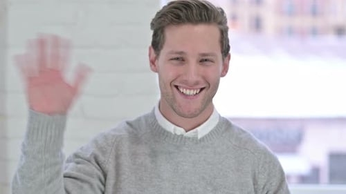 Portrait of Attractive Creative Young Man Waving at the Camera