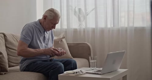 Mature Man Taking Pills with Water at Home
