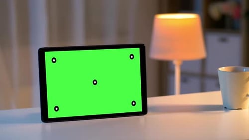 Tablet Computer with Green Screen on Table at Home