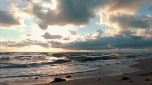 Bunter Sonnenuntergang an der Ostsee, Lettland. Langsam rollende Wellen am Strand