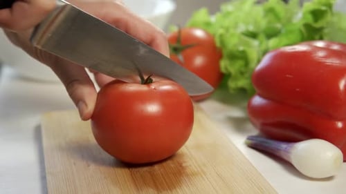 Hands Slice Fresh Tomato on Cutting Board