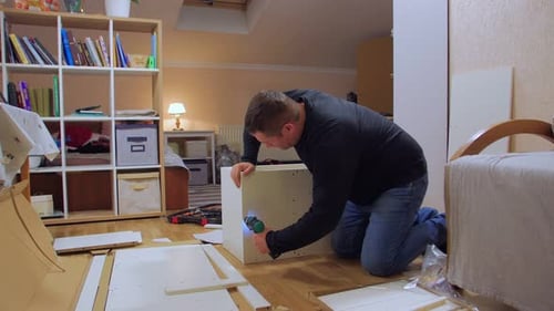 Un homme avec tournevis assemble des meubles