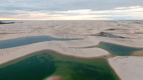 Drone recule, montrant une partie de dunes de sable blanc, avec des lagons d'eau bleuâtre, au Brésil