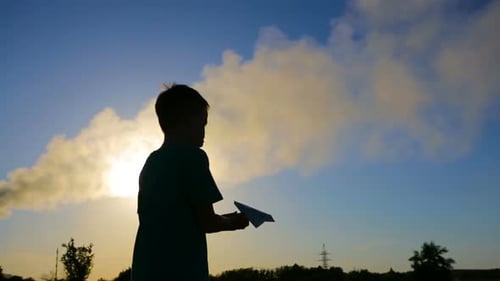 Silhouette of Boy Throwing Paper Airplane at Sunset