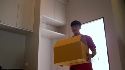 Young Adult Carrying Moving Box in New Home
