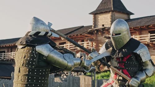 Schlacht zweier Ritter in Rüstung in der Nähe der hölzernen Festung. Mittelalterliche Metallrüstung der Ritter