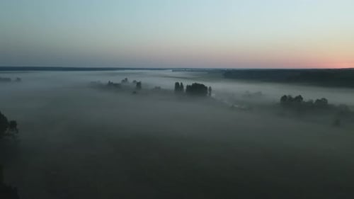 Foggy dawn in the countryside. Foggy river valley and rising sun. Aerial photography.