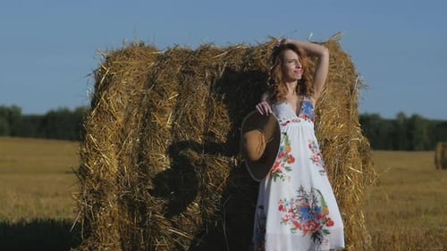Woman Poses in Floral Dress by Hay Bale