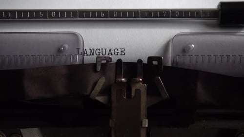 Typing word Language on retro typewriter. Close up.