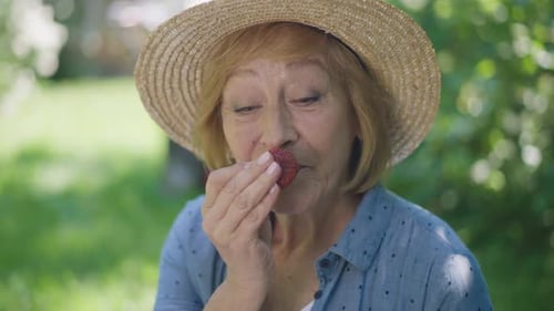 Senior Woman Smiling and Eating Fresh Strawberry