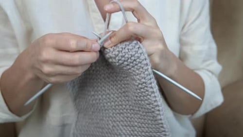 Nahaufnahme weiblicher Hände beim Stricken.