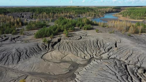 Flying above the abandoned quarry with forest and lake in autumn.