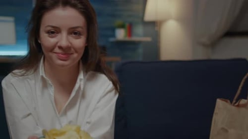 Portrait of Young Woman Holding Bowl of Chips Sitting on Sofa
