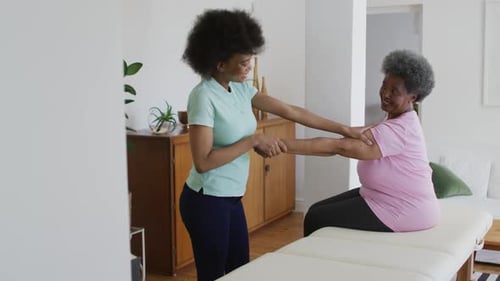 Young Woman Assists Senior Woman With Exercise