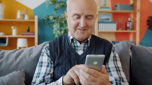 Senior Man Using Smartphone Indoors on Couch