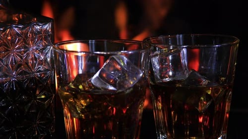 Deux verres et une carafe de whisky près de la cheminée