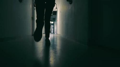 Person Walking Down Dark Lit Hallway Low Angle