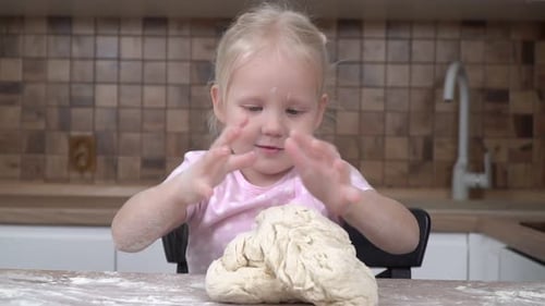 Adorable Child Kneads Dough in Kitchen