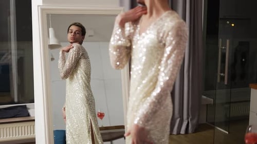 Homem sensual em um vestido se admira em pé na frente do espelho câmera lenta