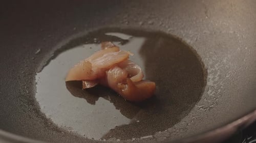 Pieces of Raw Meat Fall for Cooking of Chicken Breast in Frying Black Pan