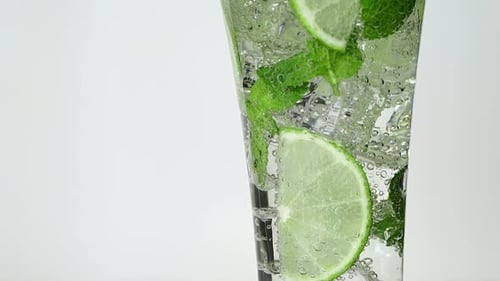 Nahaufnahme von Sodawasser im Glas mit frischen Scheiben Limette, Minze und Eis auf dem Tisch Mojito Cocktail