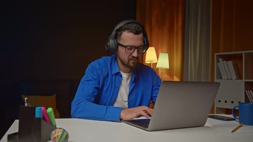 Man with Headphones Working on Laptop at Home
