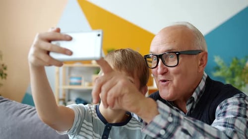 Smiling Boy Taking Selfie with Grandfather Indoors