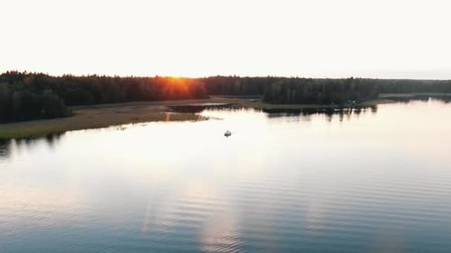 Motorboat Sails on River Against Sunset Behind Autumn Forest