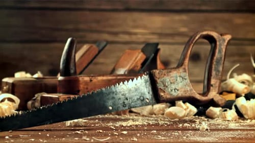 A Saw Falls on a Table with Sawdust