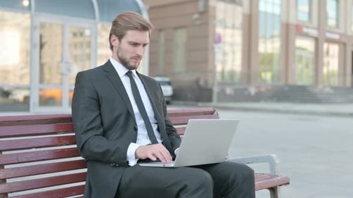 Businessman Working on Laptop in City Park