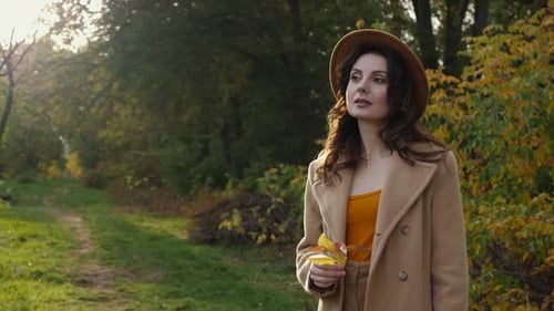 Stylish Woman Holding Leaves in Autumn Park