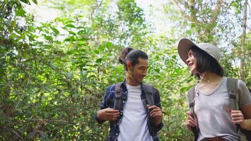 Young Asian man and Caucasian woman friend traveling walk with happiness in the forest together.