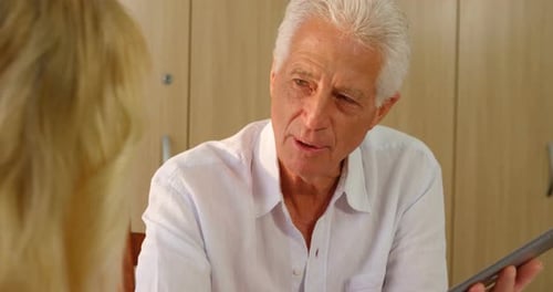 Senior Man Discussing Tablet with Blonde Woman