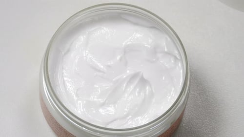 Cosmetic Spatula Scooping White Cream from Jar