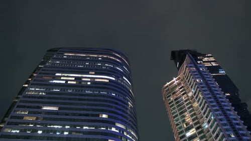 timelapse of skyscrapers with moving night clouds. illumination of the night city