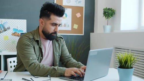 Trabajador de oficina mestizo enojado que usa la computadora, luego golpea la mesa y sale del lugar de trabajo
