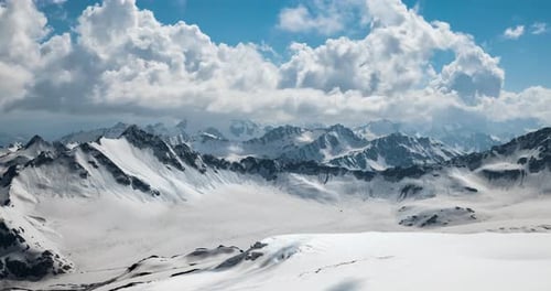 Air Flight Through Mountain Clouds Over Beautiful Snowcapped Peaks of Mountains and Glaciers