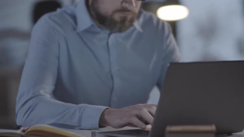 Exhausted Man Working in Office in Evening