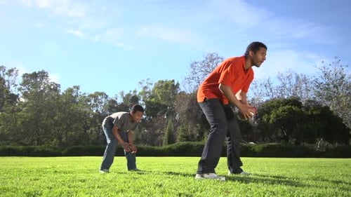 Father and Son Play American Football in Park