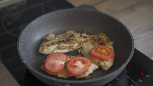 Woman Fries Fish in a Pan with Tomatoes and Grated Cheese