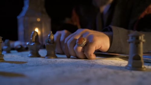 Man Moves Chess Pieces on Historic Map Table