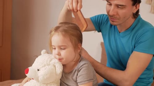 Loving Father Combing Daughter's Hair at Home