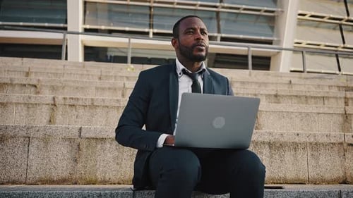 Pensive African American Man Independent Contractor Working on Laptop Outdoor Tracking Shot Slow